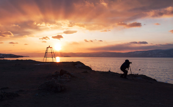 Silhouette of a photographer on the LAke Baikal during sunset moment