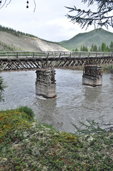Wooden bridge in Yakutia across the mountain river.