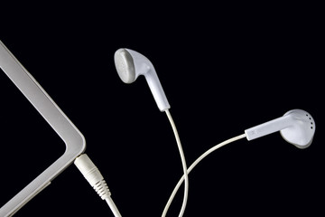 tablet and earphone on black background