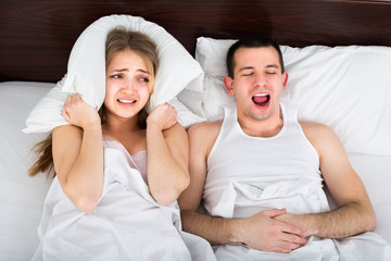 Young woman disturbed with partner snores .