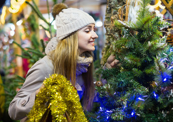 Fototapeta na wymiar Young cheerful smiling woman buying Xmas tree at festive fair