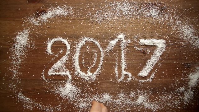 People strew coconut flakes around figures on a wooden table. Coconut flakes around figures. 2017.