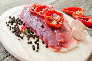 Raw fillet of duck with garlic and paprika, sprinkle with salt and pepper on a cutting board on a gray wooden table