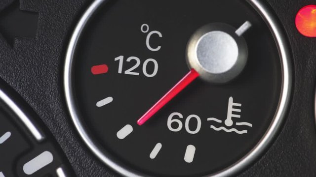 Color close up footage of a car's coolant temperature gauge with the indicator needle moving.