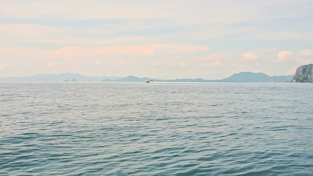 panorama of tranquil azure sea against distant cliffy islands and blue sky with pink clouds in tropics