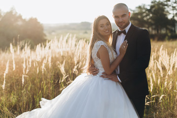 Stylish bride and bearded muscular groom posing on the wedding