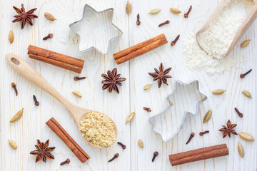 Christmas background with different spices, flour and cookie cutters on white wooden table,...