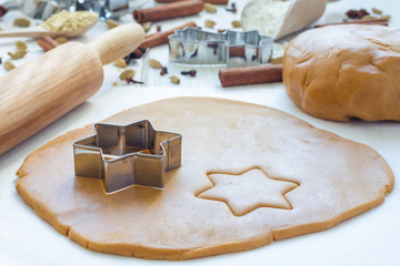 Making gingerbread cookies. Dough, metal cutter and rolling pen on wooden table, spices on background, horizontal