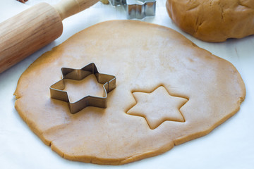 Making gingerbread cookies. Dough, metal cutter and rolling pen on wooden table, horizontal