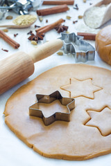Making gingerbread cookies. Dough, metal cutter and rolling pen on wooden table, spices on background, vertical