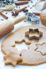 Making gingerbread cookies. Dough, metal cutter and rolling pen on wooden table, spices on background, vertical
