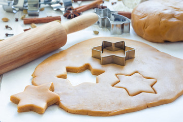 Making gingerbread cookies. Dough, metal cutter and rolling pen on wooden table, spices on background, horizontal