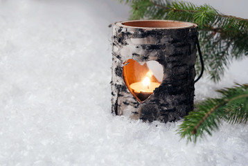 Wood candle holder in the snow with pine