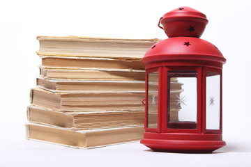 stack of old books. red lamp with candle