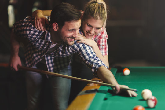 Couple playing billiards together