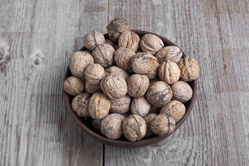 walnuts in a bowl on a wooden background