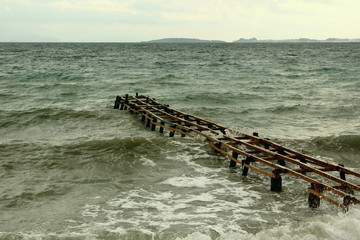 Obraz premium rough sea on shore with beach and wooden pie