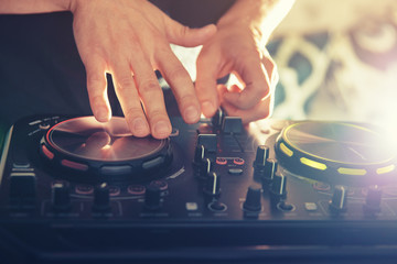 DJ turntable console mixer controlling with two hand in concert nightclub stage.