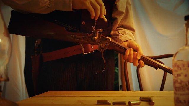 An old west type man loading his sharps buffalo rifle then stands ready and alert