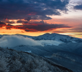 Beautiful landscape in the winter mountains at sunrise. Dramatic colorful sky. View of snow-covered hills.