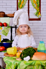 Little girl in a cook clothes rolls  circle of dough on  table