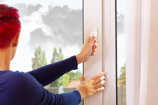 Frau schlie&szlig;t das Fenster wegen Regenwolken