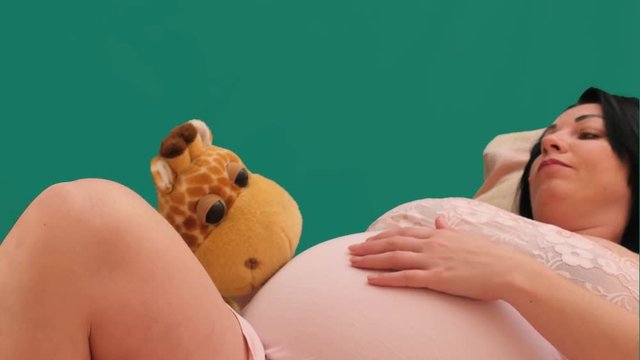 Reclining pregnant woman with toy touch the belly chroma key