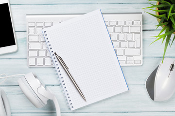 Wooden desk with notepad, headphones, pc, phone and plant