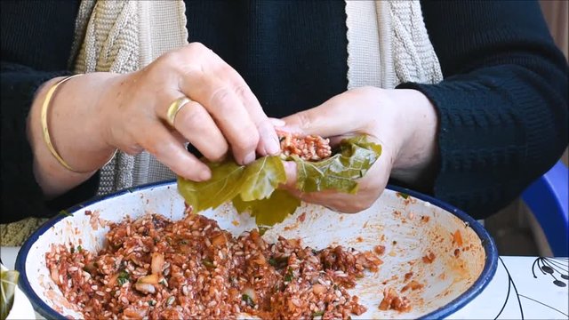 Turkish woman making Sarma - Traditional Turkish food. Grape leaves stuffed with rice and minced meat.