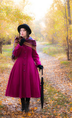 girl in a bright crimson coat walking in forest sunny autumn day