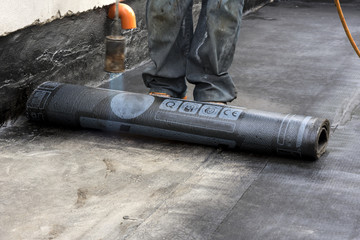 worker while burning the waterproof membrane on a roof