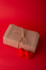 Gift box and red heart shapes on red background