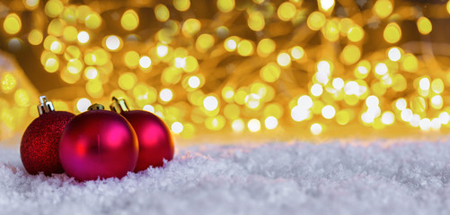 Weihnachtlicher Hintergrund mit Bokeh und Christbaumkugeln auf Schnee