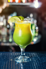 bright yellow-green cocktail garnished with lime. Classic alcohol cocktails, cocktails at the bar, alcoholic drinks, soft drinks, tasty cocktails