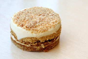 multi layer cake with vanilla yogurt cream and walnuts on wooden background with copy space
