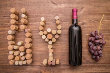 Bottles of wine, glasses made with cork and grapes on a wooden background