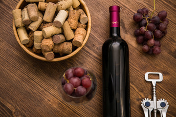 Bottles of wine, glasses of wine, grapes and cork wine on a wooden background.