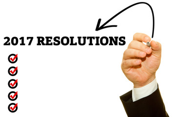 Businessman hand writing 2017 RESOLUTIONS on a transparent wipe board