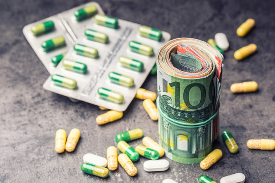 Euro money and medicaments. Euro coins and pills. Rolled euro banknotes stacked on each other in different positions and freely pills around scattered. Toned image.
