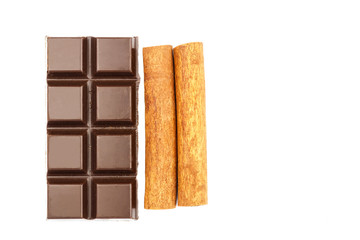 Dark chocolate bar and cinnamon sticks isolated on white background, top view.
