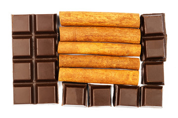 Dark chocolate bar and cinnamon sticks isolated on white background, top view.