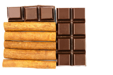 Dark chocolate bar and cinnamon sticks isolated on white background, top view.