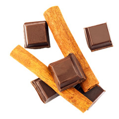 Dark chocolate cubes and cinnamon sticks isolated on white background, top view.