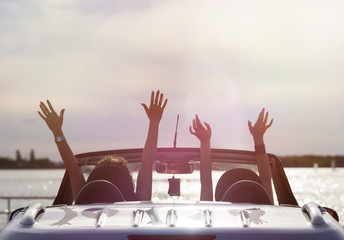 two happy traveler woman in cabriolet car with raised hands
