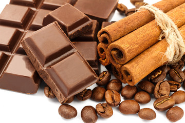 Dark chocolate bar, cubes, cinnamon sticks and coffee beans isolated on white background.