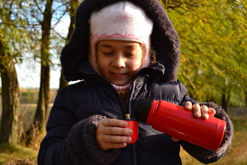 Чтобы согреться холодным днем девочка наливает чай из термоса
