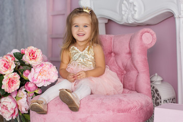 Pretty child girl is sitting on pink chair