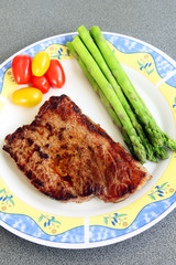served delicious piece of medium grilled beef steak with tomatos and asparagus