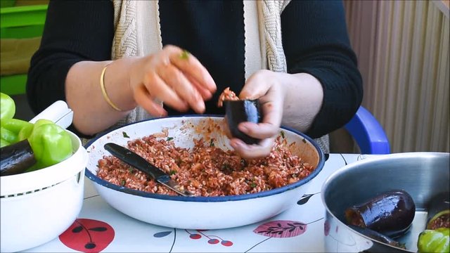 Turkish woman making Dolma - Traditional Turkish food. Pepper and eggplant stuffed with rice and minced meat. 