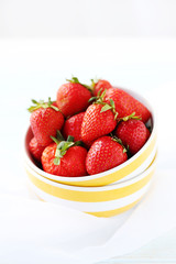 Fresh and tasty strawberries in bowl on a white wooden table